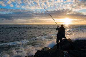 Man crab-fishing off Oregon coast, with dramatic sunset